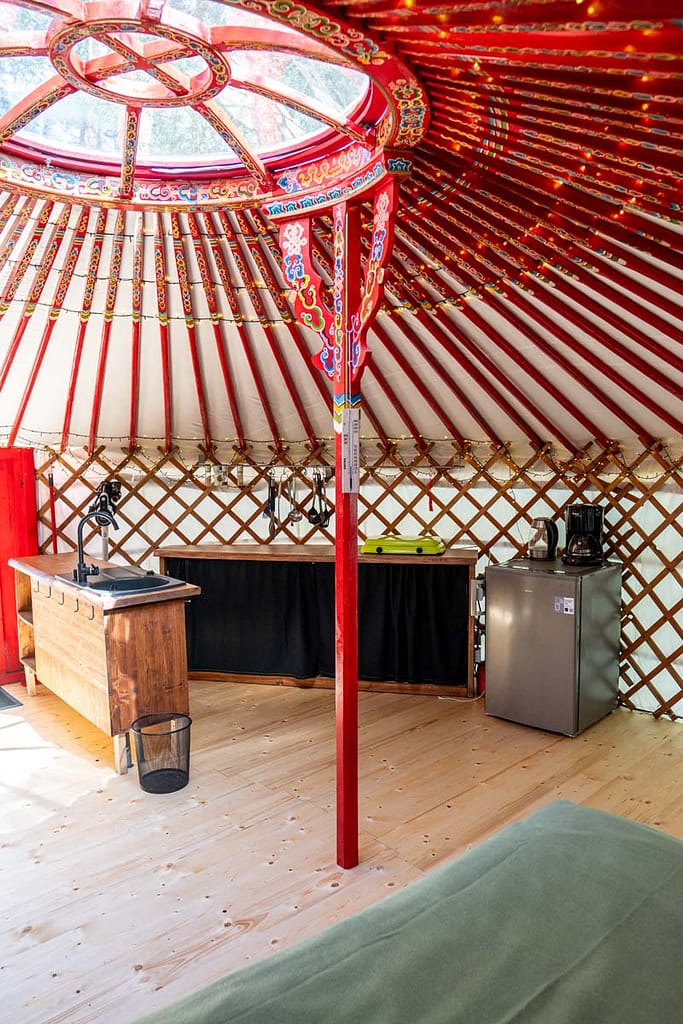 Interiér jurty Rozárky s kuchyňským koutem, dřevěnou pracovní deskou, lednicí, kávovarem.