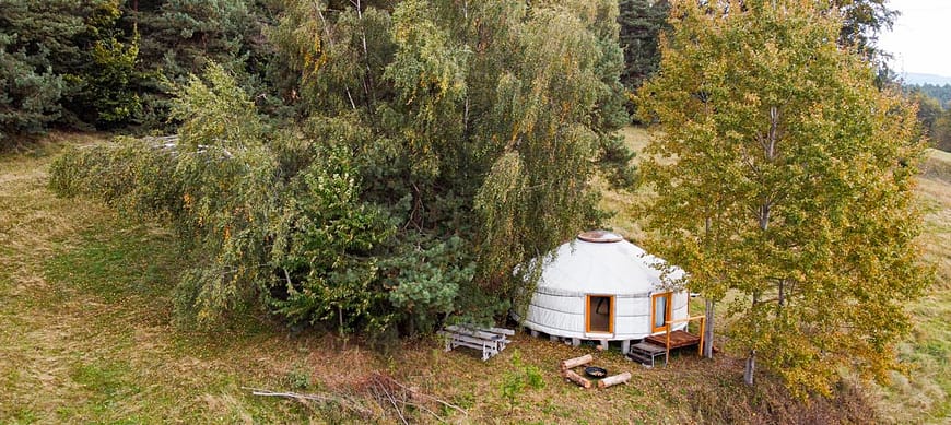 jurta Andělka a její klidné okolí. Pro soukromí objímají jurtu stromy. Pro venkovní posezení si můžete vybrat teplíčko u ohně nebo opodál posezení pod břízou.