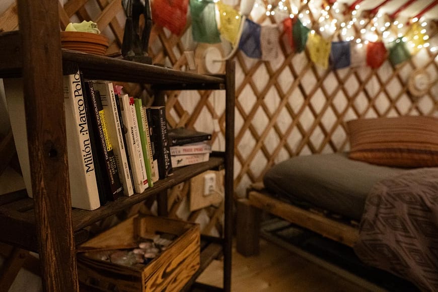 Večerní interiér jurty Rozárky s plnou knihovnou zajímavé, naučné, seberozvojové četby.