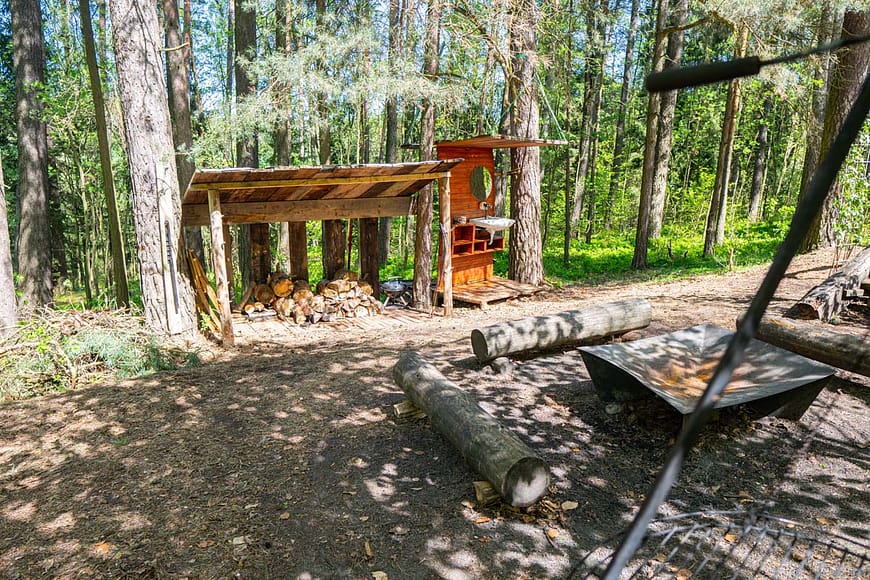 Pohled na exteriér jurty Rozárky. Venkovní koupelna, dřevník spolu s ohništěm vhodný pro večerní posezení s kytarou v ruce.