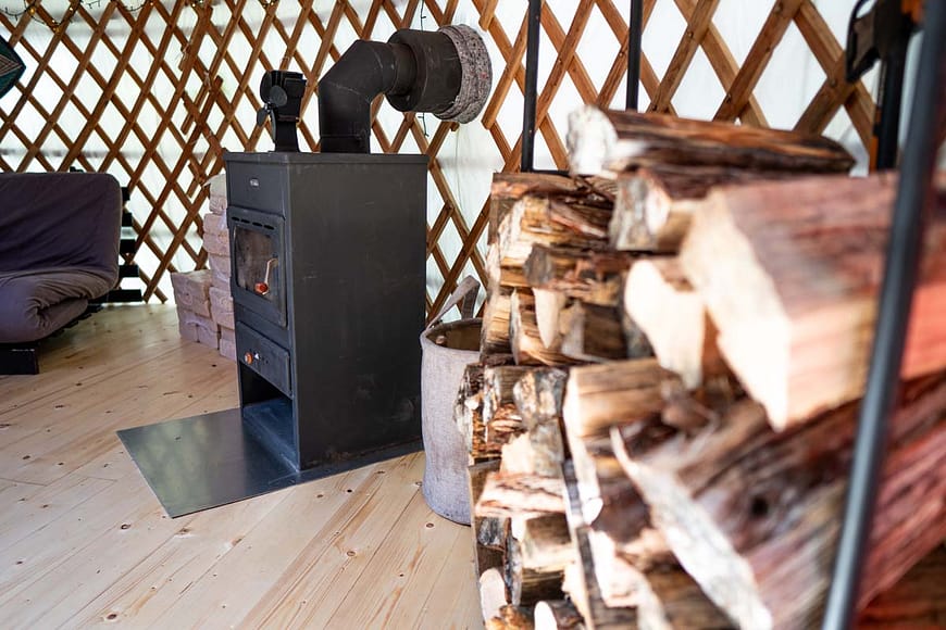 Interiér jurty s kamny na dřevo, zásobou polínek. Uvnitř útulné prostředí vhodné k odpočinku i zimnímu pobytu